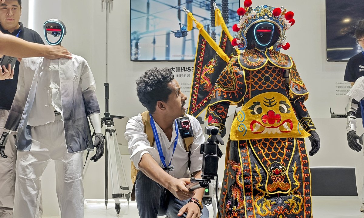 An overseas visitor takes a photo with a domestically produced humanoid robot at the International Advanced Air Mobility Expo in Shanghai on July 23, 2025. Photo: VCG