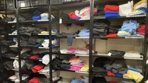 Telford Crisis Support Black metal shelves holding various labelled items of clothing in different colours
